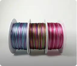 Trois bobines de fins cordons tissés en dégradé, tons pastel, olive et fuchsia — Maison Satab