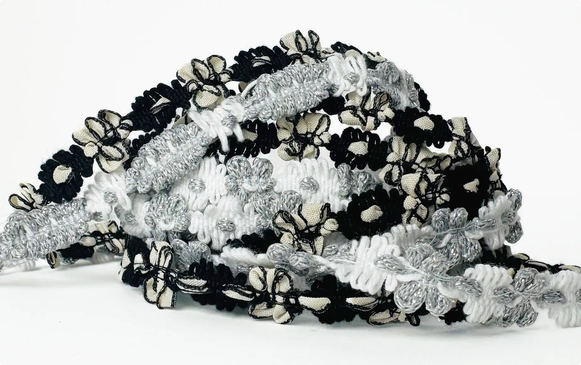 Galons fantaisie entrelacés en noir, blanc écru et fils argentés, à motifs de fleurs et de boucles — Maison Satab