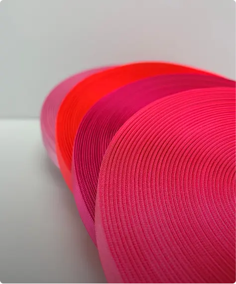 Rouleaux de rubans gros-grain déroulés en dégradé de rouge et de rose sur fond clair — Maison Satab