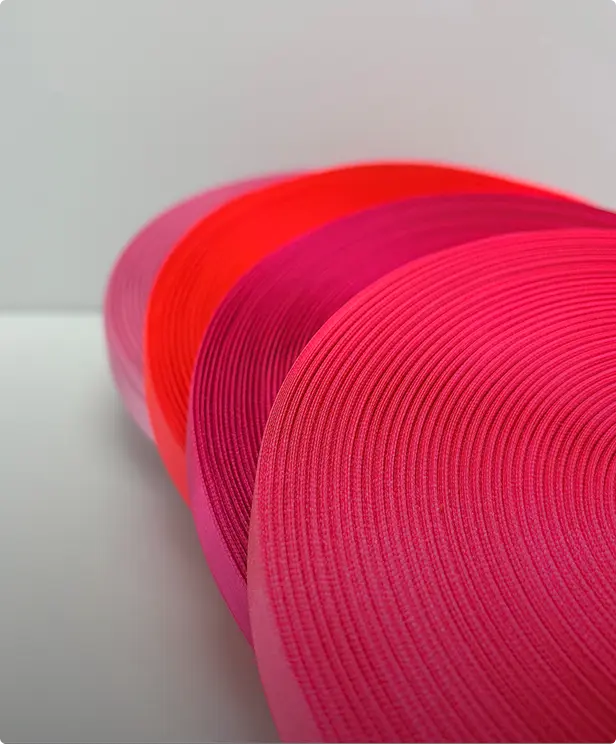 Rouleaux de rubans gros-grain déroulés en dégradé de rouge et de rose sur fond clair — Maison Satab