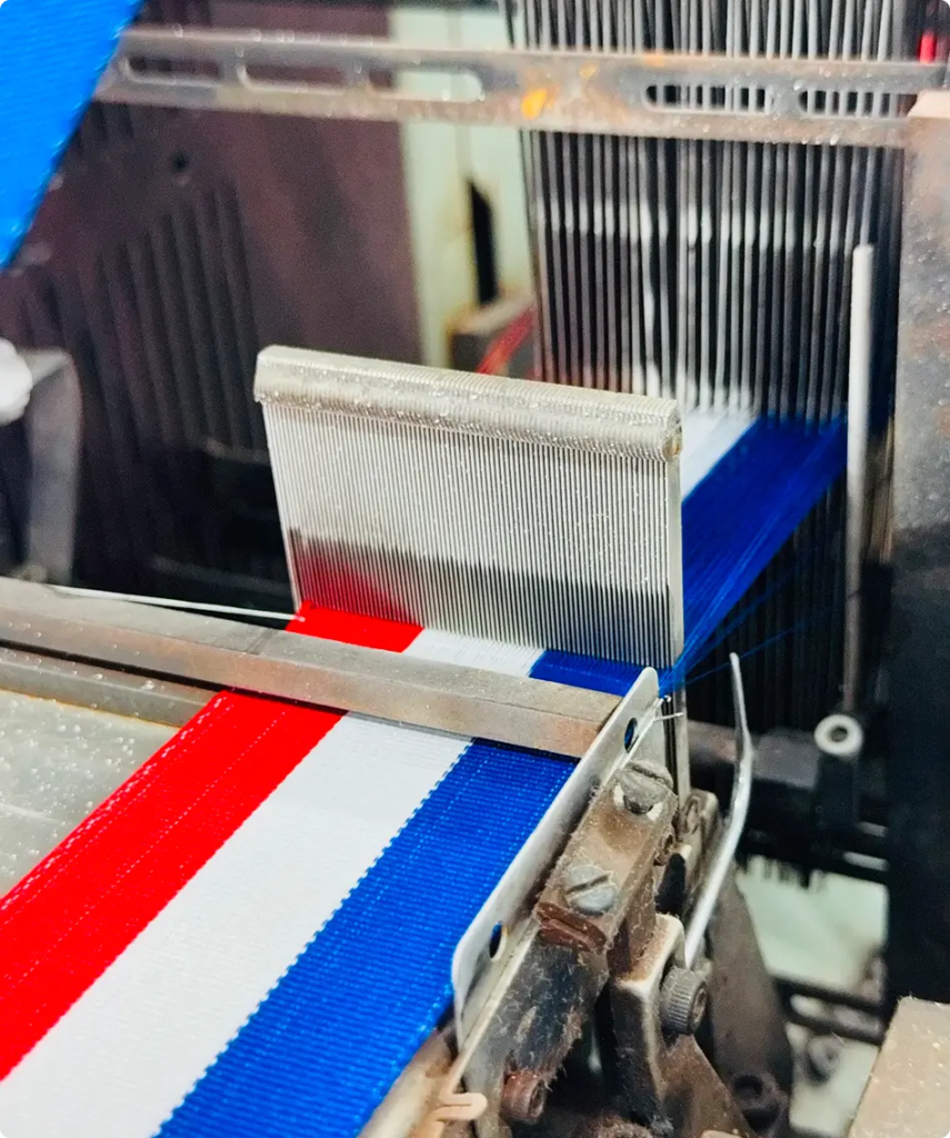 Métier à tisser en train de produire un ruban bleu, blanc et rouge — Maison Satab