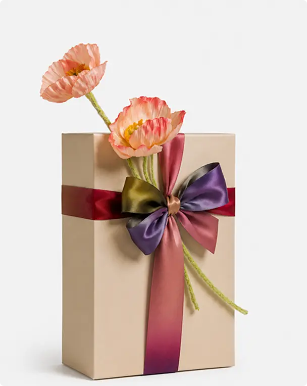 Coffret beige ceint de rubans bordeaux et prune, surmonté d’un nœud et de fleurs de pavot en papier — Maison Satab