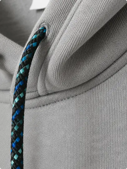 Cordon tressé bleu et vert glissé dans la capuche d’un sweat gris — Maison Satab