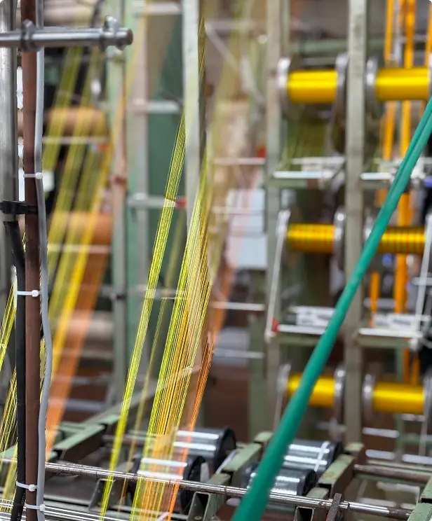 Métier en production, cônes de fil dorés et fils tendus sur les organes de la machine — Maison Satab